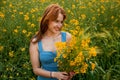 The girl holds in her hands a bouquet of rapeseed and spikelets of wheat