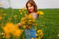 The girl holds in her hands a bouquet of rapeseed and spikelets of wheat