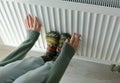 The girl holds her hands and feet on the batteries close-up, the heating season, the concept of heating resources Royalty Free Stock Photo