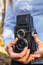 A girl holds in her hands an old film photo camera in the spring forest Royalty Free Stock Photo