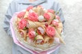 Girl holds in her hands an original bouquet consisting of pink flowers of a rose and various sweets