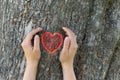 Girl holds her hands in protection gesture for saving nature. Glowing red heart