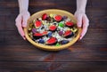 Girl holds in her hands wooden plate with beautiful dish oatmeal with a fresh fruit