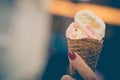 A girl holds ice cream cones with strawberry and vanilla