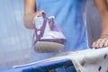 The girl holds an iron on an ironing board with a ferry and irons things. Cleaning service of the apartment. Blue T Royalty Free Stock Photo