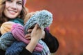 The girl holds a large number of knitted hats in her hands. Man is out of focus.Handmade caps. Knitting for the soul. Woman`s