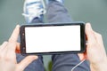 The girl holds a mobile phone in her hands and looks at its screen, the headphone cord is visible, in the background the girl Royalty Free Stock Photo