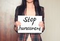 Girl holds a paper sheet with text stop harassment