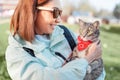 Girl holds pet in her arms and smiles looking at her favorite cute cat. Walking with a pet in the nearest city Park. Concept