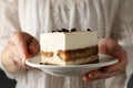 Girl holds plate with delicious tiramisu close up. Selective focus