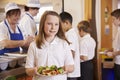 Girl holds a plate of food in school cafeteria, head turned Royalty Free Stock Photo