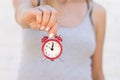 The girl holds a red alarm clock on the outstretched hand against the background of a white brick wall Royalty Free Stock Photo