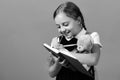 Girl holds teddy bear and writes in blue notebook Royalty Free Stock Photo