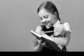 Girl holds teddy bear and writes in blue notebook Royalty Free Stock Photo