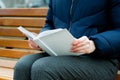 A girl holds a white book in her hands.