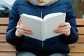 A girl holds a white book in her hands.