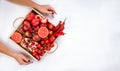 Girl holds wooden tray with fresh red vegetables and fruits on grey background. Healthy eating vegetarian concept. Royalty Free Stock Photo