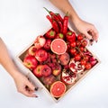 Girl holds wooden tray with fresh red vegetables and fruits on white background. Healthy eating vegetarian concept. Royalty Free Stock Photo