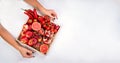 Girl holds wooden tray with fresh red vegetables and fruits on white background. Healthy eating vegetarian concept. Royalty Free Stock Photo