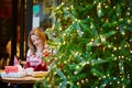 Girl in holiday sweater drinking coffee or hot chocolate in cafe decorated for Christmas Royalty Free Stock Photo