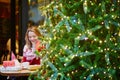 Girl in holiday sweater drinking coffee or hot chocolate in cafe decorated for Christmas Royalty Free Stock Photo