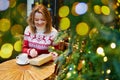 Girl in holiday sweater drinking coffee or hot chocolate in cafe decorated for Christmas Royalty Free Stock Photo