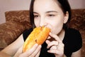 The girl at home bites off a delicious and appetizing hot dog Royalty Free Stock Photo