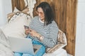 Girl at home on her bed uses laptop and phone Royalty Free Stock Photo