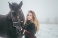 A girl with a horse in a field in winter