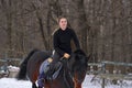 A girl on a horse jumps gallops. A girl trains riding a horse in a small paddock. A cloudy winter day Royalty Free Stock Photo