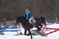 A girl on a horse jumps gallops. A girl trains riding a horse in a small paddock. A cloudy winter day Royalty Free Stock Photo