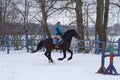 A girl on a horse jumps gallops. A girl trains riding a horse in a small paddock. A cloudy winter day Royalty Free Stock Photo