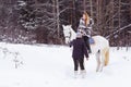 Girl, horse trainer and white horse in a winter