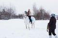 Girl, horse trainer and white horse on a winter