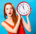 Girl with huge clock on blue background. Royalty Free Stock Photo