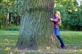 Girl is hugging a big tree in autumn park. Royalty Free Stock Photo