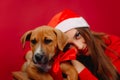 The girl hugs her puppy. Photo on a red background. Holiday and gifts concept
