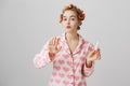 Girl is in hurry to make herself beautiful. Portrait of good-looking glamorous woman in hair curlers and nightwear with Royalty Free Stock Photo