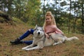 A girl with a husky walks in the forest.