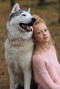 A girl with a husky walks in the forest.