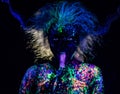 The girl in the image of the devil, contact lenses and horns. Woman paints her tongue in ultraviolet paint. fluorescent powder. Royalty Free Stock Photo