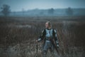 Girl in image of Jeanne d`Arc in armor and with sword in her hands stands on meadow. Back view.