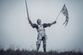 Girl in image of Jeanne d`Arc stands in armor and issues battle cry with sword raised up and flag in her hands.