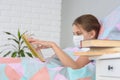 A girl with influenza is reading a book, books are on the nightstand in front of her, focusing on the girl