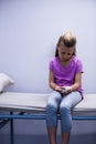 Girl with injured hand sitting on stretcher bed Royalty Free Stock Photo