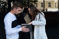 Girl in jacket and glasses looks in surprise at gift box. Guy gives gift to his girlfriend Royalty Free Stock Photo