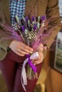 a girl in a jacket holds a bouquet of dried flowers in her hands. lilac color scheme