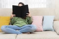 Girl sitting on a couch reading a book Royalty Free Stock Photo