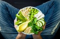 Girl in jeans holding vegan, detox green Buddha bowl with quinoa, avocado, cucumber, spinach, tomatoes, mung bean sprouts, edamame Royalty Free Stock Photo