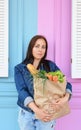 Girl in a jeans jacket is holding a paper bag with food in her hands